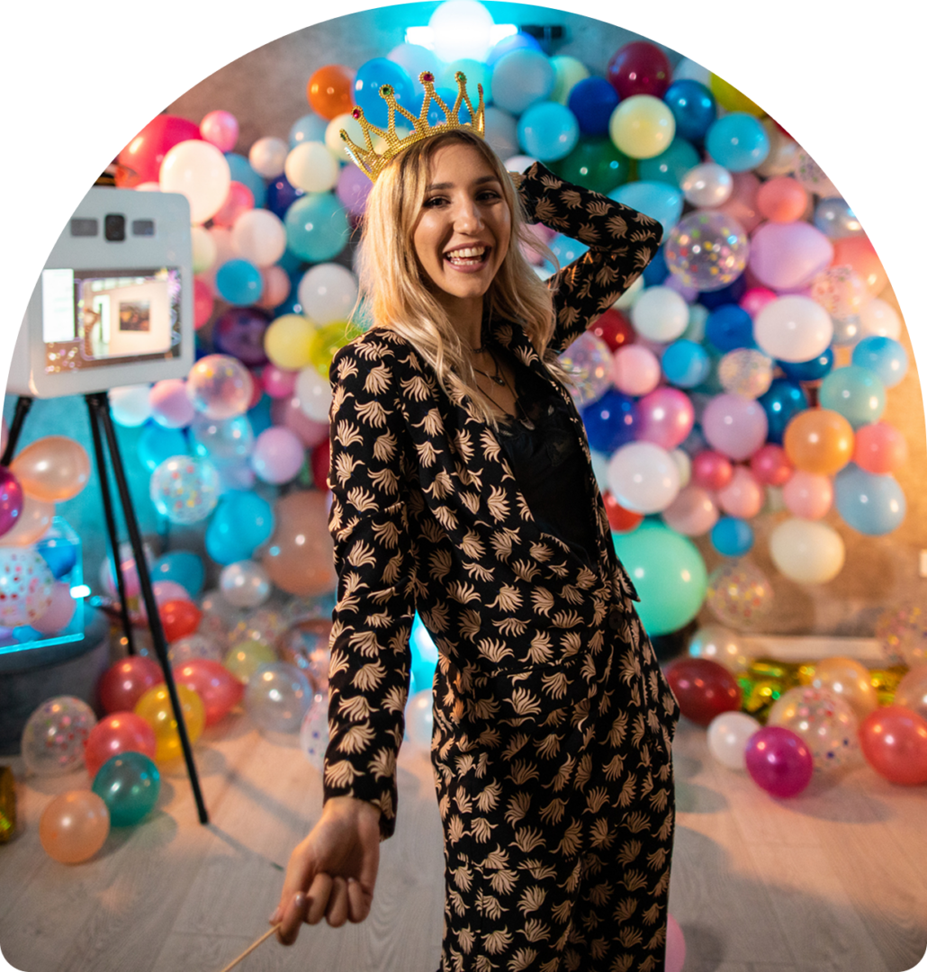 Woman smiling with crown, colorful balloons background.