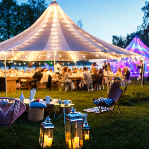 Outdoor evening party under illuminated tents.