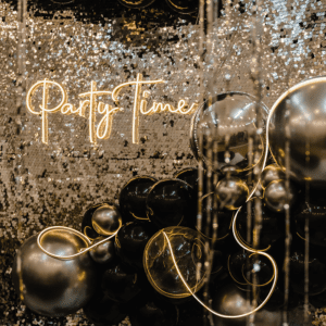 Party Time" sign with silver, black balloons.