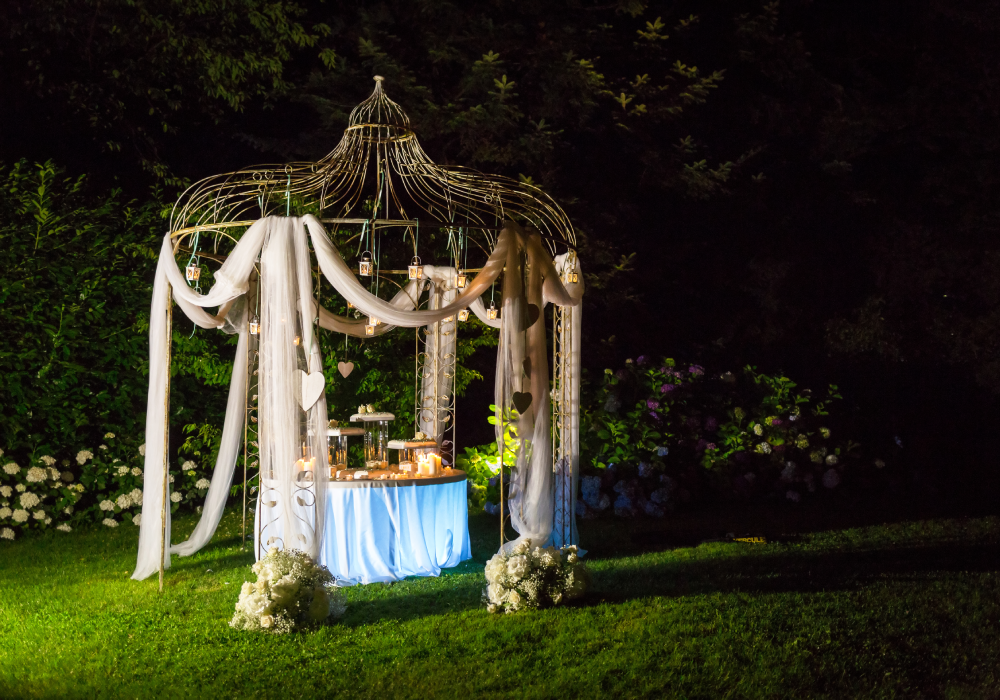 Outdoor gazebo decorated with lights and drapes.